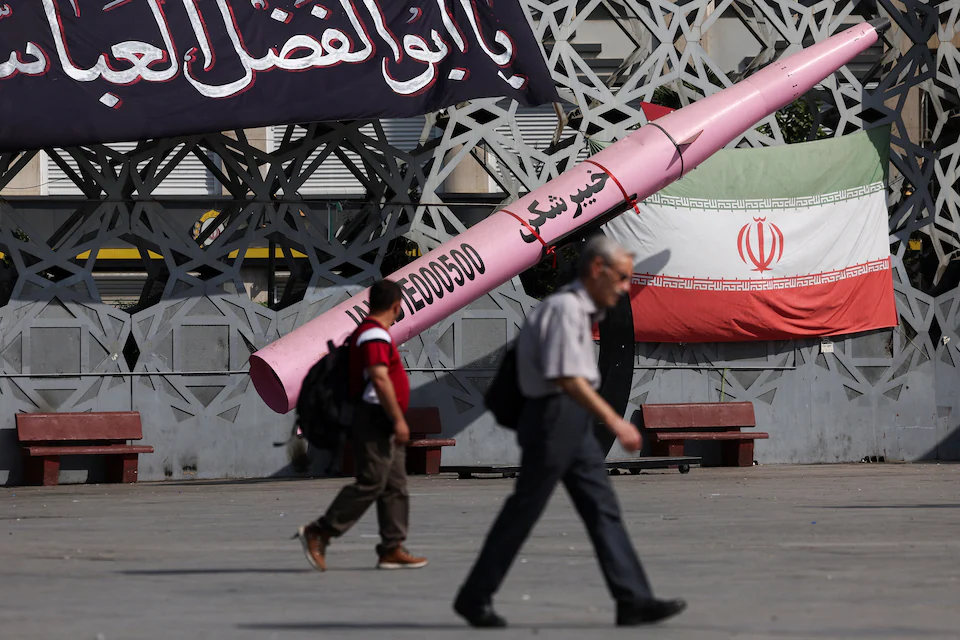 People pass replica of a missile in Tehran